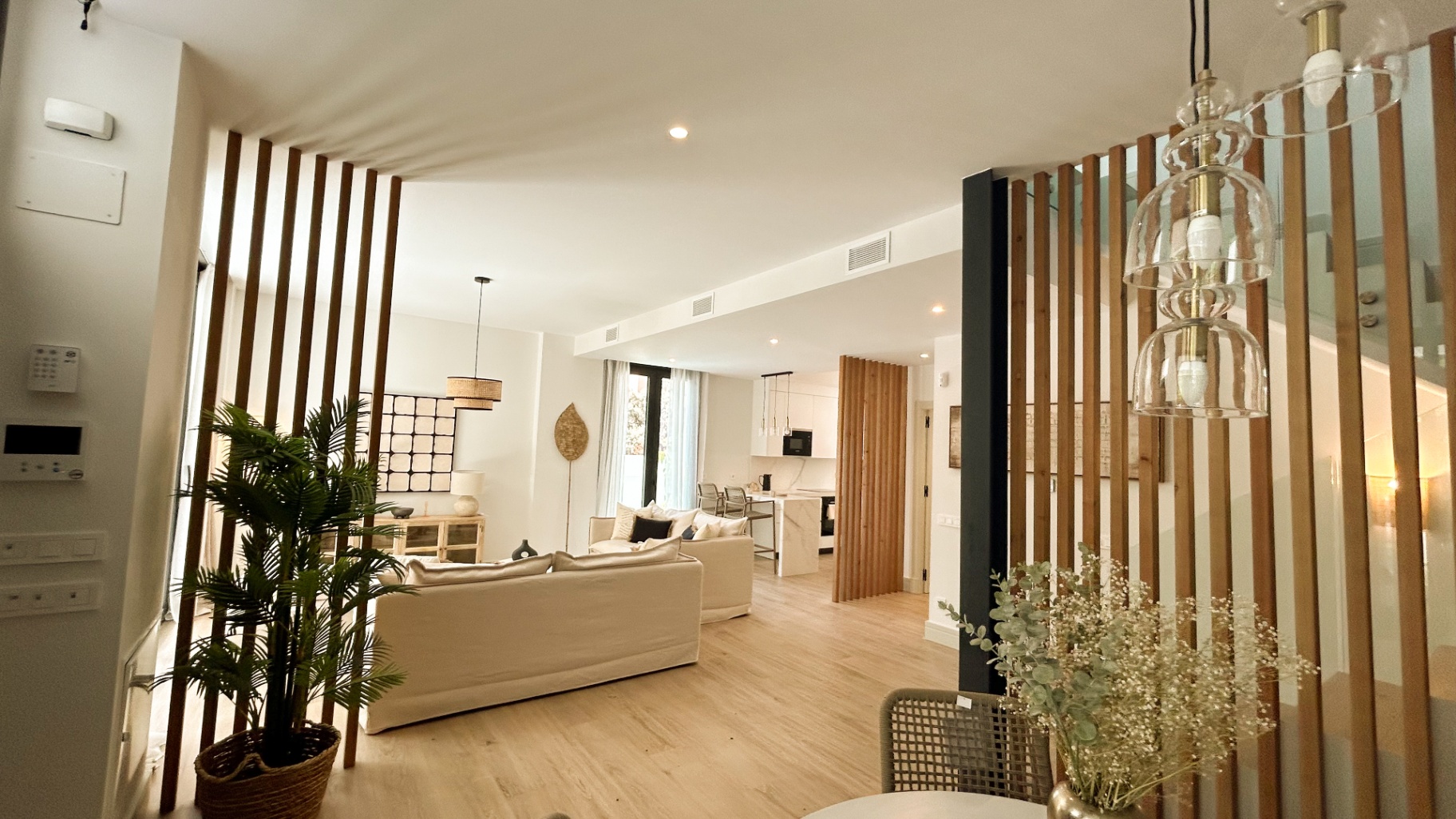 Salón abierto con celosías de madera y cocina al fondo