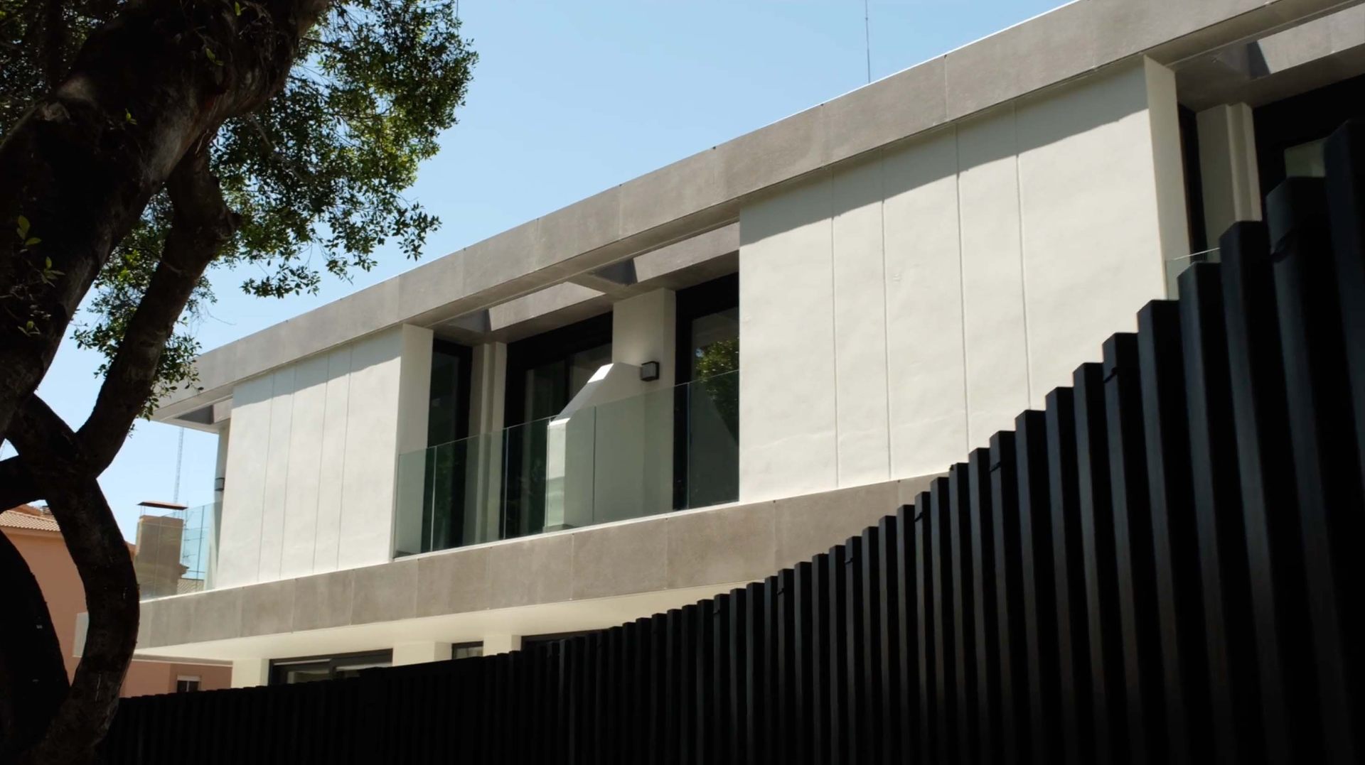 Fachada contemporánea de piedra clara con balcón y celosía negra